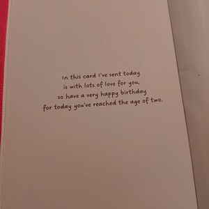 May include: A white birthday greeting card with a pink edge featuring the black printed text: In this card I've sent today is with lots of love for you, so have a very happy birthday for today you've reached the age of two.