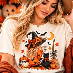 Puede incluir: Una camiseta color crema con un gráfico de una persona de pelo rubio largo con un sombrero de bruja negro con un girasol y un lazo de cuadros. El diseño incluye un gato negro, calabazas, una escoba, murciélagos, una luna creciente y una taza con el texto Witch Please.