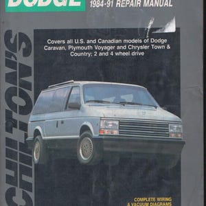 May include: A Chilton's repair manual for 1984-91 Dodge Caravan and Voyager models. The grey cover features a silver minivan, the text 'Dodge Caravan & Voyager 1984-91 Repair Manual', and notes coverage for U.S. and Canadian models, including wiring diagrams.