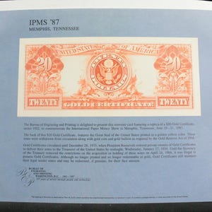 May include: A souvenir card featuring a replica of a 20 dollar Gold Certificate from 1922. The card includes the text IPMS '87 Memphis, Tennessee, and historical information about the currency printed on a light blue background.