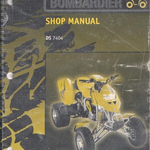 May include: A spiral-bound Bombardier shop manual with a dark gray and yellow cover. The cover features the text "BOMBARDIER", "SHOP MANUAL", "DS 7404", and "704 100 005". A yellow all-terrain vehicle is pictured in the center of the cover.