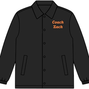 May include: A black coach jacket featuring a pointed collar, long sleeves with elastic cuffs, and a front snap-button closure. The text "Coach Zach" is printed in orange on the upper left chest area. The jacket includes two vertical side pockets.