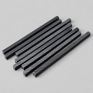 May include: A set of six long, thin, rectangular rods featuring a dark gray and black carbon fiber weave pattern. Each rod has a flat, elongated shape with a consistent width and length, arranged in a parallel, slightly overlapping formation.