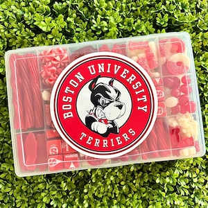 May include: A clear plastic box filled with an assortment of red candies, including licorice, gummy rings, and hard candies. A circular sticker with the words "Boston University Terriers" and a bulldog mascot is centered on the box.