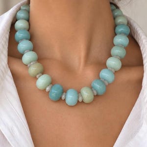 The Palm Beach necklace worn with a white shirt: large round blue quartz and white moonstone beads, with small pale spacers between them.