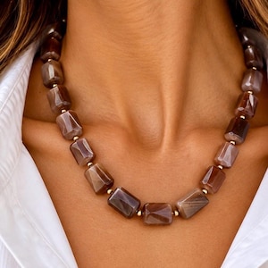 The Delphine necklace worn with an open white shirt: faceted chocolate moonstone beads in brown and taupe, separated by small gold-filled accents.