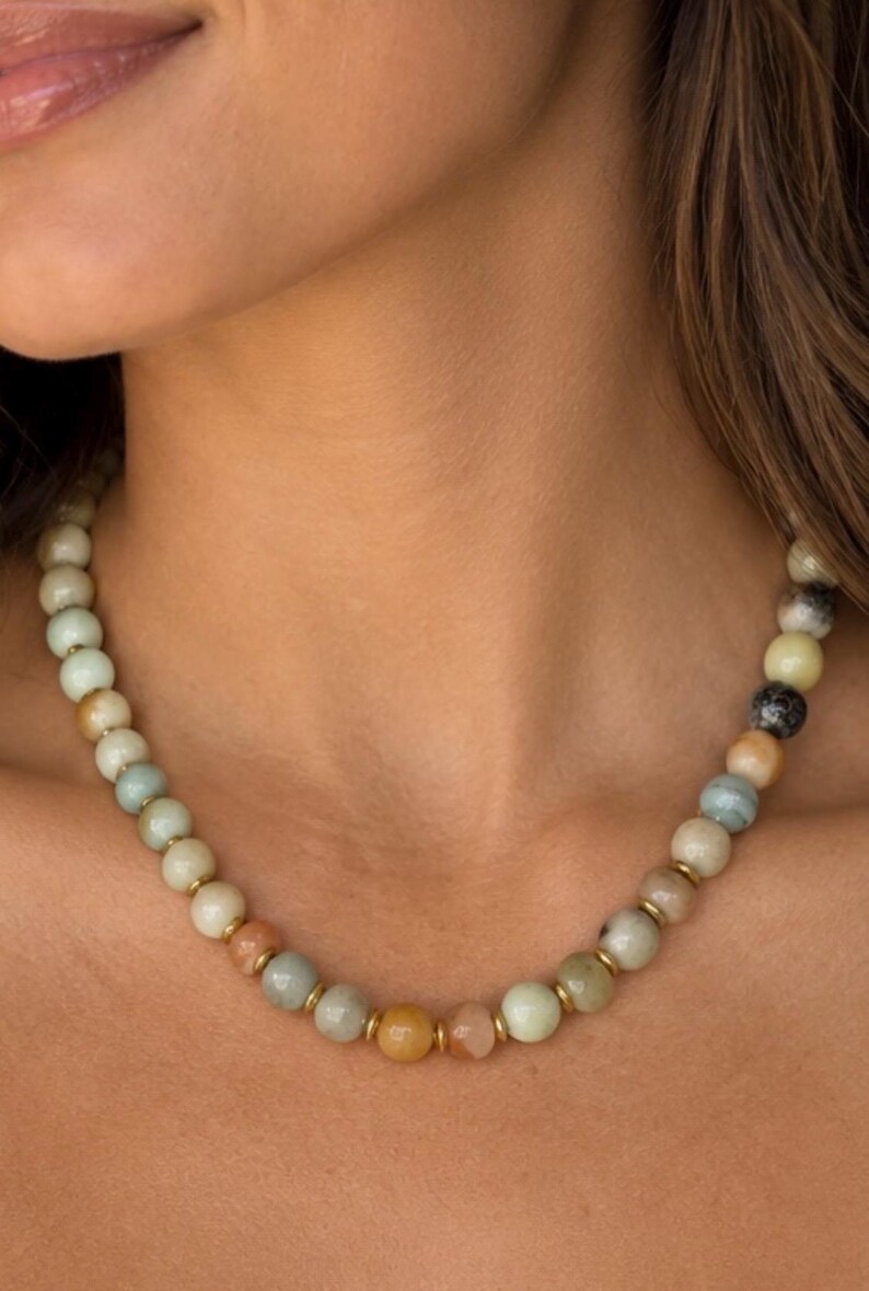 The Carmel necklace worn at the collarbone: round amazonite beads in pale green, tan and gray tones with small gold-colored spacers.
