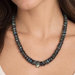 The Aspen necklace worn with a white top: graduated dark gray labradorite beads with a larger faceted stone at the center.