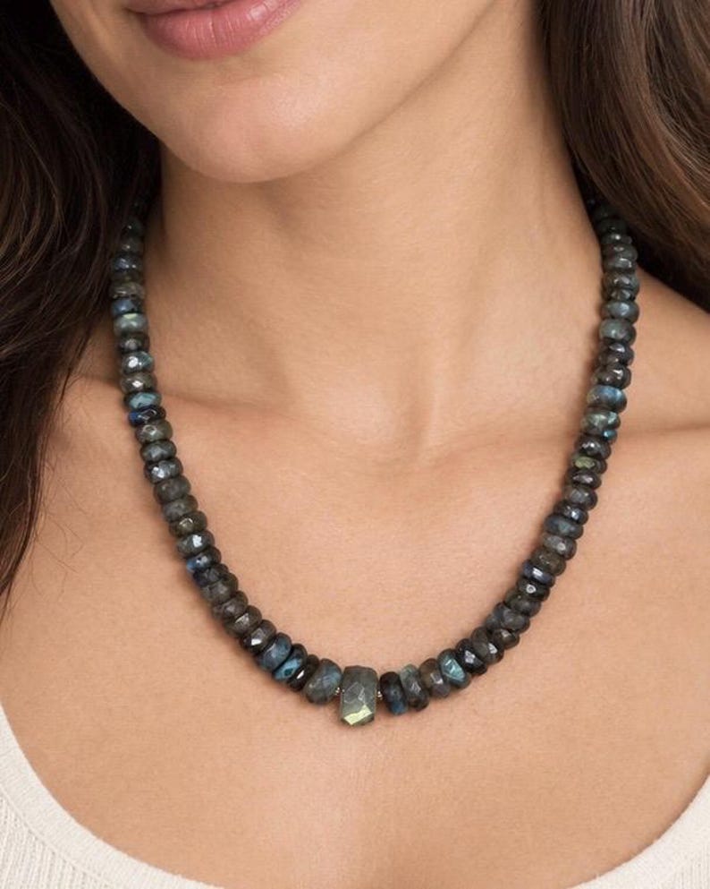 The Aspen necklace worn with a white top: graduated dark gray labradorite beads with a larger faceted stone at the center.