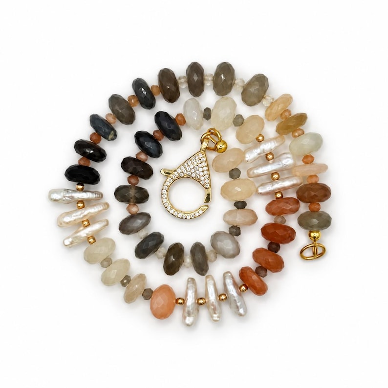 The Capri necklace arranged in a circle on white: faceted moonstone in smoky gray, cream and warm peach, freshwater pearls, gold-filled accents and a decorative gold-plated clasp.