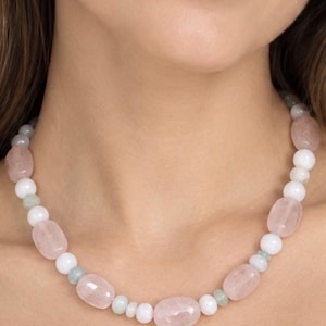 The Camille necklace worn at the collarbone: pale pink rose quartz ovals, round white beads and small pale green spacers.