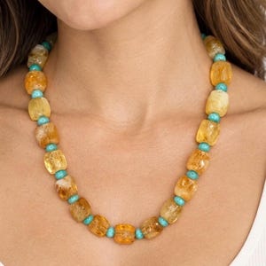 The Portofino necklace worn with a white top: golden-yellow citrine nuggets alternating with small round turquoise-colored beads.