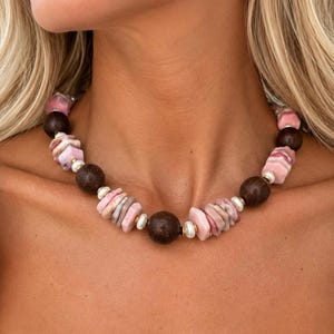 The Paloma necklace worn at the collarbone: clusters of pink opal chips with round brown wood beads and small white pearls.
