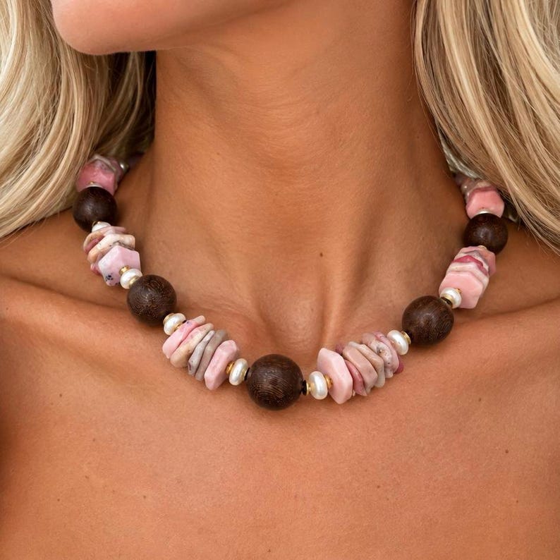 The Paloma necklace worn at the collarbone: clusters of pink opal chips with round brown wood beads and small white pearls.