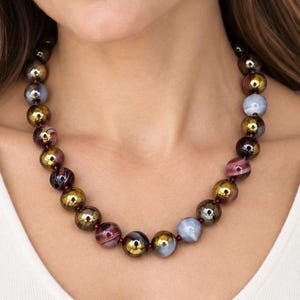 The Bordeaux necklace worn with a white top: round dyed ruby agate beads in burgundy, gray and gold tones with small garnet spacers.