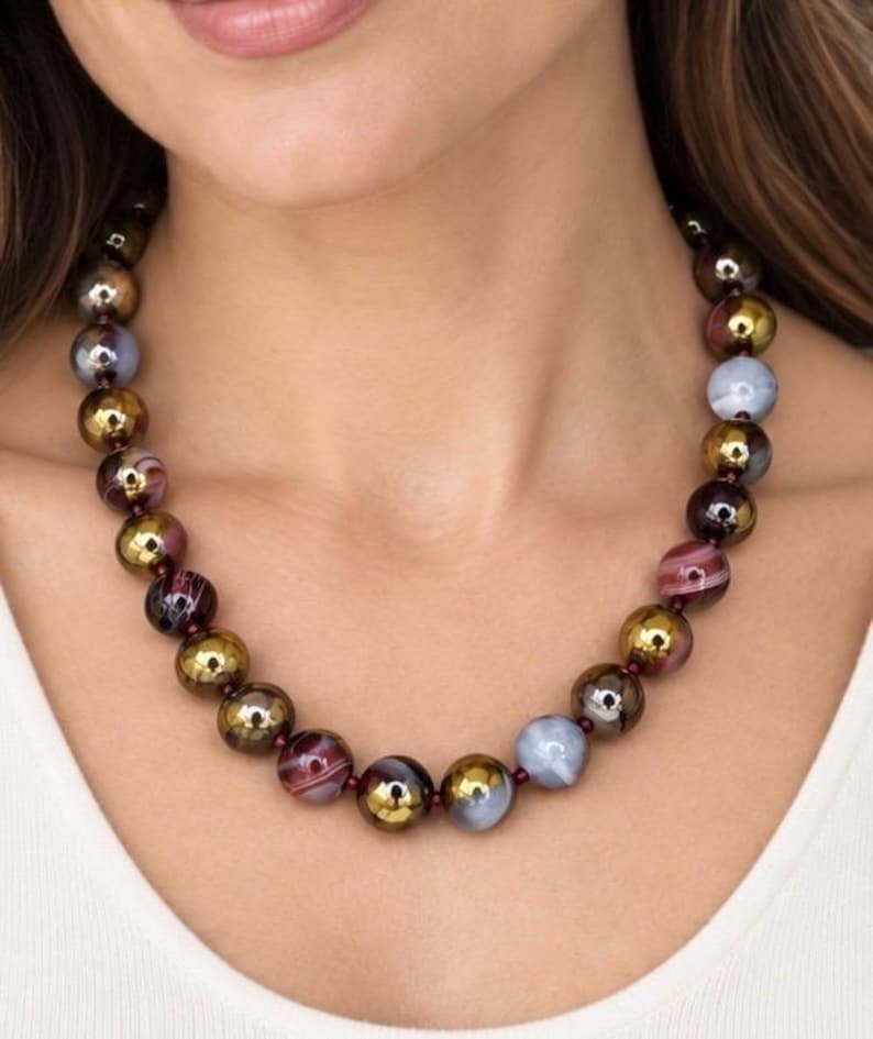 The Bordeaux necklace worn with a white top: round dyed ruby agate beads in burgundy, gray and gold tones with small garnet spacers.