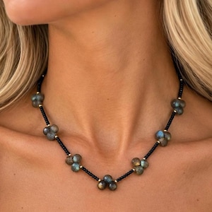 The Sloane necklace worn at the collarbone: clusters of gray-green labradorite beads linked by slim black spinel sections and gold-filled accents.