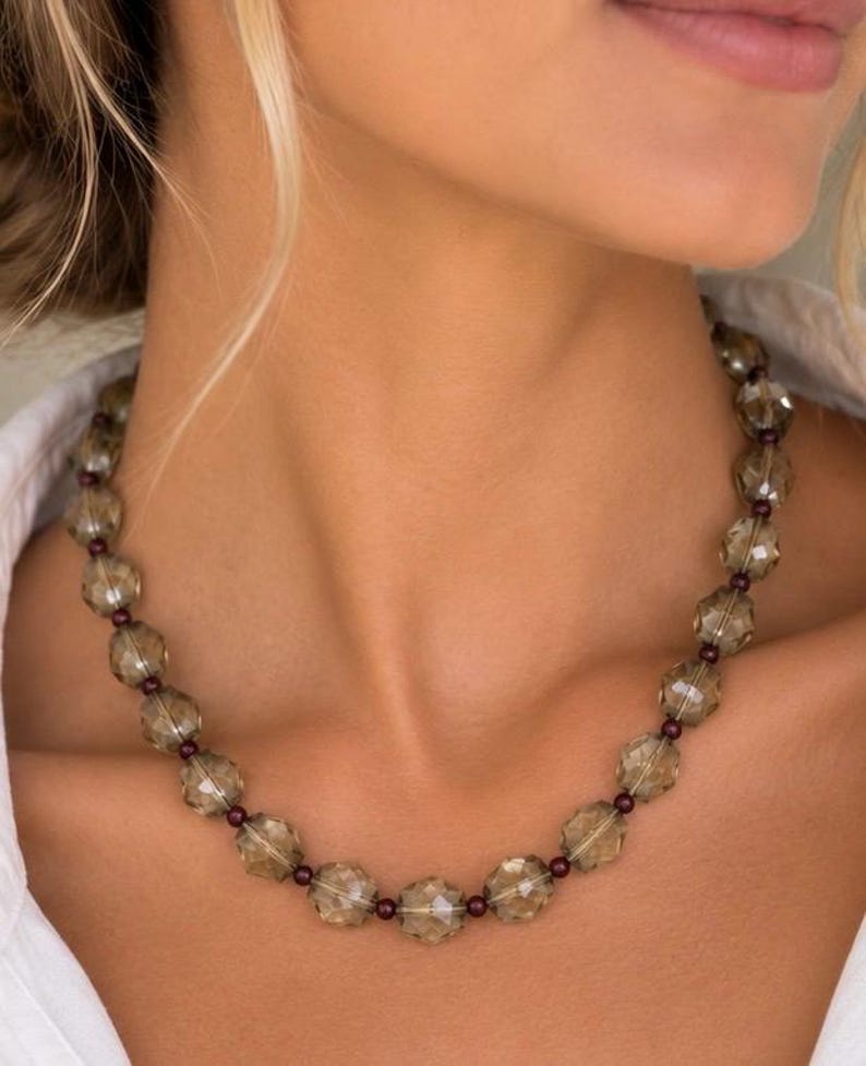 The Florence necklace worn at the collarbone: faceted smoky quartz beads alternating with small dark red garnet beads.