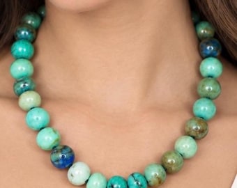 May include: A beaded necklace featuring round, polished stones in varying shades of turquoise, teal, and deep blue. The beads exhibit natural marbling and color variations, strung together to form a continuous circular strand around the neck.