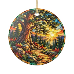 May include: A round hanging ornament featuring a stained glass style illustration of a large tree beside a stone path. The scene depicts a sunrise over a forest of pine trees with vibrant orange, yellow, green, and blue colors throughout.