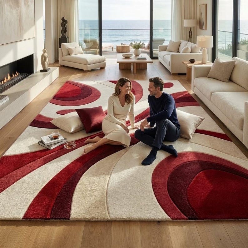 May include: A large area rug featuring a bold, abstract pattern of sweeping curves in shades of deep red, burgundy, and cream. The rug has a plush, textured pile and covers a significant portion of the floor, showcasing a modern, flowing design.