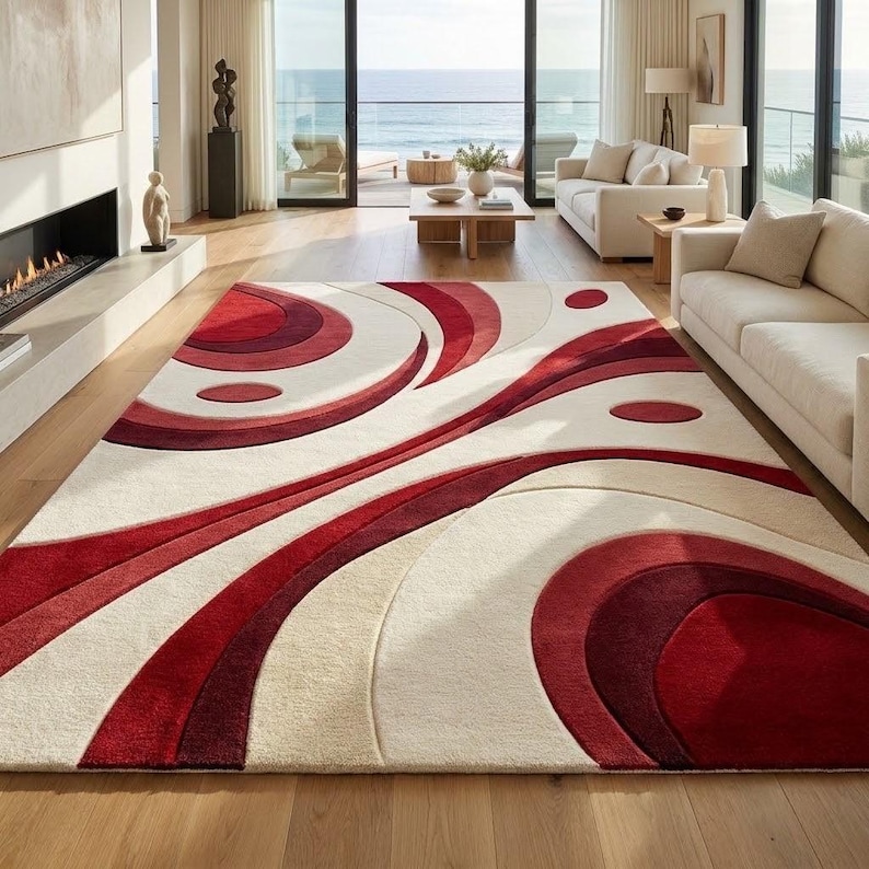 May include: A rectangular area rug featuring a bold abstract pattern of concentric circles and sweeping curved lines in shades of deep red, burgundy, and cream. The design utilizes varying pile heights to create a three-dimensional effect.