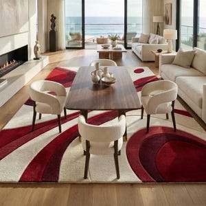 May include: A large rectangular area rug featuring a bold, abstract pattern of sweeping curves and circular shapes in shades of deep red, burgundy, and cream. The rug is positioned under a wooden dining table with three cream-colored chairs.