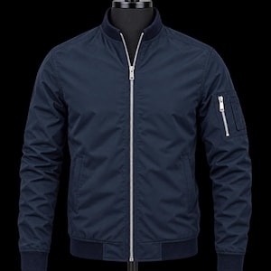 May include: A navy blue bomber jacket featuring a full-length silver metal front zipper, a ribbed collar, ribbed cuffs, and a ribbed hem. The jacket includes a utility pocket on the left sleeve with a silver zipper closure and two side pockets.