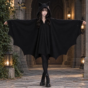 Può includere: Una mantella nera con cappuccio caratterizzata da una silhouette ad ali di pipistrello con bordi smerlati e orecchie a punta sul cappuccio. Il capo è indossato sopra leggings neri e stivali con plateau. Il logo Vyrel Outfits è visibile.