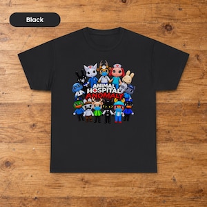 Peut inclure: Un t-shirt noir à manches courtes avec un motif coloré représentant divers animaux de dessin animé habillés en personnel médical. Le texte ANIMAL HOSPITAL ANOMALY est imprimé en lettres blanches et rouges au centre du groupe.