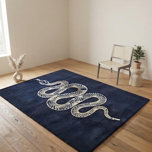 Peut inclure: Un tapis rectangulaire de couleur bleu marine profond présentant un grand motif de serpent centré. Le serpent est représenté dans une teinte crème ou blanc cassé avec un motif d'écailles détaillé et complexe sur tout son corps sinueux.