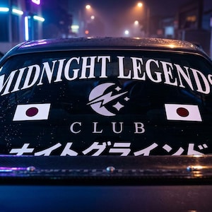 Può includere: Il lunotto posteriore di un'auto con un adesivo bianco che riporta la scritta MIDNIGHT LEGENDS CLUB, un'icona a forma di mezzaluna e fulmine, due bandiere giapponesi e testo in giapponese in basso, su uno sfondo stradale scuro.