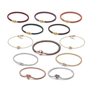 May include: A collection of twelve bracelets featuring various designs, including braided cord styles with gold-tone clasps, thin gold chains with star and heart charms, and metallic snake chains with heart-shaped infinity clasps.