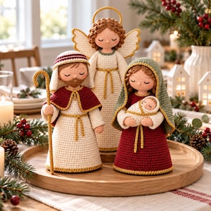 May include: A crochet nativity set featuring three figures and an infant. One figure wears a white robe with a red cape and holds a gold staff. Another figure wears a red dress with a green head covering, holding a swaddled infant. An angel figure stands behind them with white wings and a gold halo.