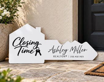 May include: A white house-shaped sign in the form of a large key with black text that reads Closing Time, Ashley Miller, REALTOR, and the phone number 232.432.1123, featuring a small graphic of two keys hanging from the letter g.