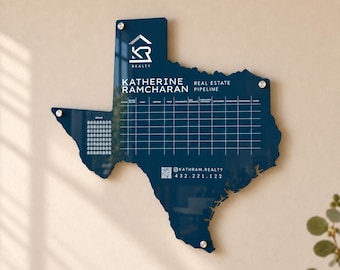 May include: A dark blue acrylic wall board shaped like the state of Texas, featuring a white grid for real estate pipeline tracking, the text Katherine Ramcharan Real Estate Pipeline, a KR Realty logo, and contact information with a QR code.