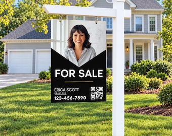 May include: A white real estate sign post holds a rectangular sign featuring a photo of a smiling person in a striped shirt. The sign displays the text FOR SALE, ERICA SCOTT REALTOR, 123-456-7890, and a QR code on a black background.