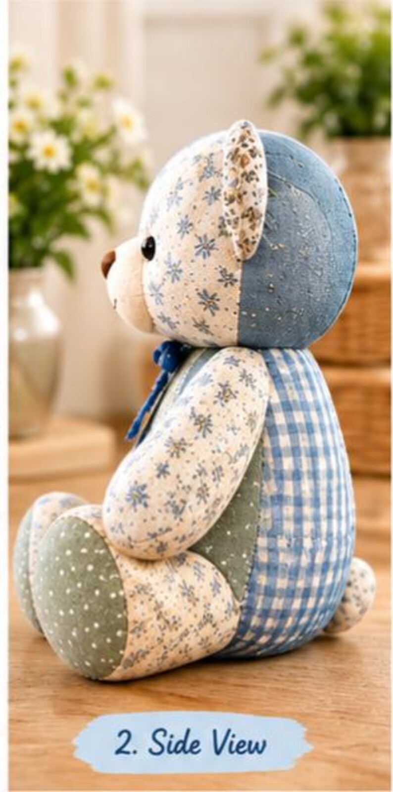 May include: A stuffed teddy bear shown from the side, featuring a patchwork design of blue and white floral fabric, blue gingham check, and green fabric with white polka dots. The bear has a brown nose and a small blue ribbon tied at the neck.