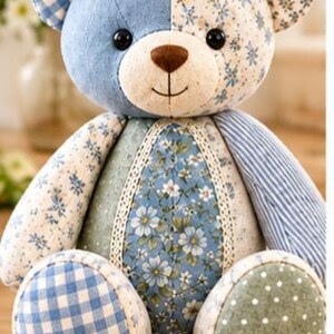 May include: A patchwork teddy bear featuring a mix of blue and white fabrics with floral, gingham, and striped patterns. The bear has a cream-coloured muzzle, a brown nose, black button eyes, and a stitched mouth. It includes lace trim details.