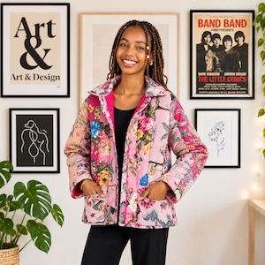 Pode incluir: Um casaco acolchoado com uma base rosa vibrante e um padrão floral multicolorido, gola, mangas compridas e dois bolsos frontais. O casaco é usado sobre uma blusa preta simples e calças pretas, apresentando um fecho de botões frontal.