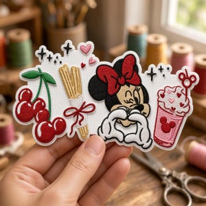 May include: An embroidered patch featuring a cluster of red cherries, a bundle of churros tied with a red ribbon, a cartoon mouse character with a red bow making a heart shape with hands, and a pink drink with a mouse-shaped stirrer.