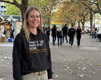 May include: A black hooded sweatshirt featuring white text that reads "THAT'S THE HARD PART DONE" and orange text below that reads "MORE HARD PARTS TO COME" with a dashed line graphic. The hoodie includes a front kangaroo pocket and long sleeves.