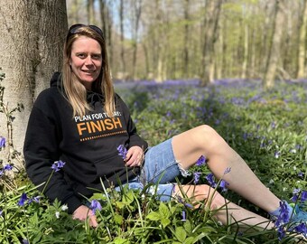 May include: A black hooded sweatshirt featuring the white and orange text PLAN FOR TODAY: FINISH with a dashed line underneath, paired with blue denim shorts. The garment has long sleeves, a front kangaroo pocket, and a drawstring hood.
