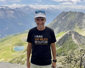 May include: A black short-sleeved t-shirt featuring white and orange text that reads I RAN 100 MILES AND ALL I GOT WAS THIS LOUSY T-SHIRT. The shirt has a crew neckline and is made of a solid black fabric with clear, bold lettering printed on the chest.