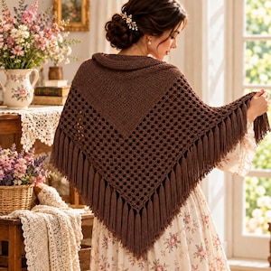 May include: A dark brown triangular crochet shawl featuring a solid knit top section and a lower section with an openwork grid pattern. The edges of the shawl are finished with long, matching brown fringe tassels that hang along the bottom border.
