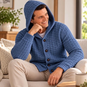 May include: A blue hooded cardigan featuring a textured waffle-knit pattern, a front button closure with dark brown buttons, long sleeves with ribbed cuffs, and a hood. The garment is worn over a plain white shirt and paired with light-colored trousers.