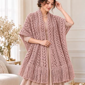 May include: A dusty rose crochet shawl featuring an intricate openwork diamond pattern and vertical ribbed columns. The garment is finished with a long, straight fringe along the bottom hem, creating a textured, layered appearance over a matching dress.