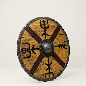 Pode incluir: Um escudo circular de madeira com acabamento amarelo e detalhes em forma de cruz vermelho-escuro. A superfície apresenta quatro símbolos rúnicos pretos distintos e um umbo metálico central. A borda externa é reforçada com metal cinza.