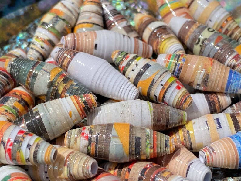 May include: Close-up of a collection of colorful paper beads. The beads are made from rolled up pieces of paper and have a variety of patterns and colors.
