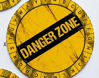 May include: A circular yellow sign with a distressed texture featuring a black diagonal stripe across the centre with the text DANGER ZONE in bold yellow letters. The outer border contains the alphabet from A to Z in black capital letters.